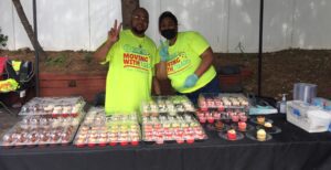 Two men standing in front of a table with cupcakes.