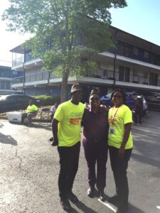 Three people in yellow shirts standing in front of a building.
