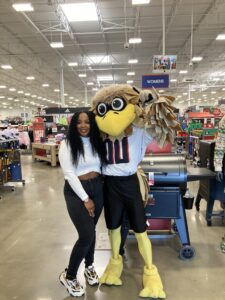 A woman posing with a mascot in a store.