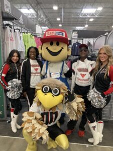 A group of girls posing with a mascot in a store.
