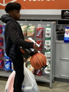 A young man holding a basketball in a store.