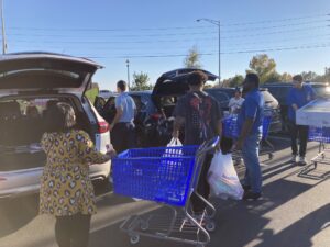 A group of people standing in a parking lot with shopping carts.