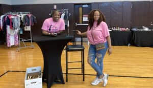 Two women standing next to a table in a gymnasium.