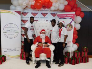 A group of people posing in front of a santa claus chair.
