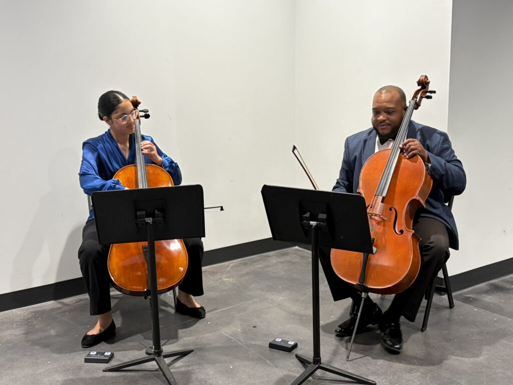 Two cellists seated and playing