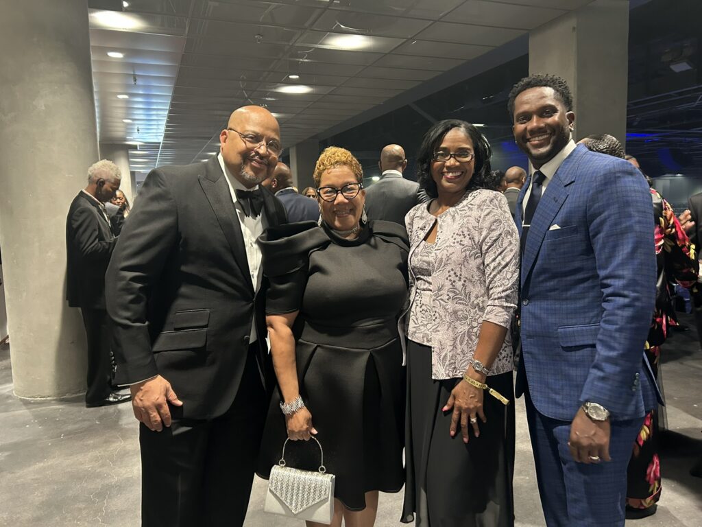 Four people in formal attire smiling together