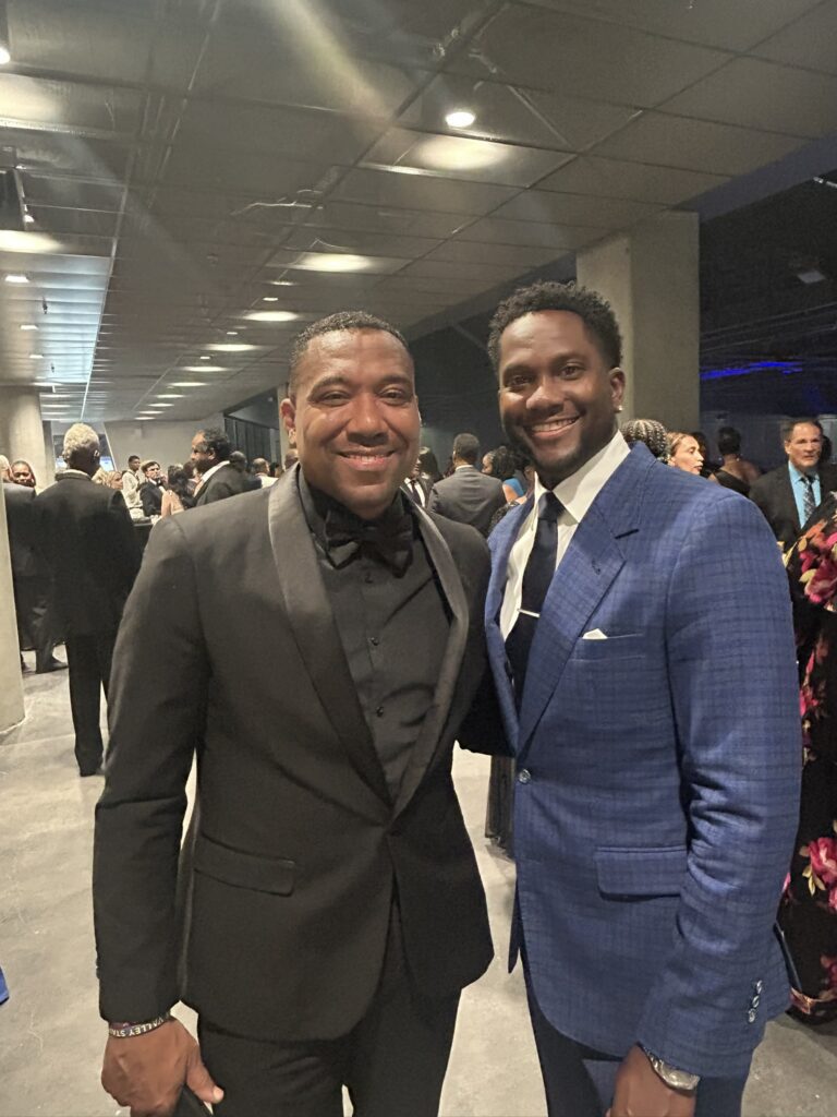 Two men in suits smiling at formal event