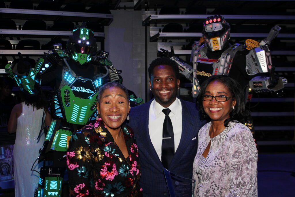 Three people smiling with glowing robots behind