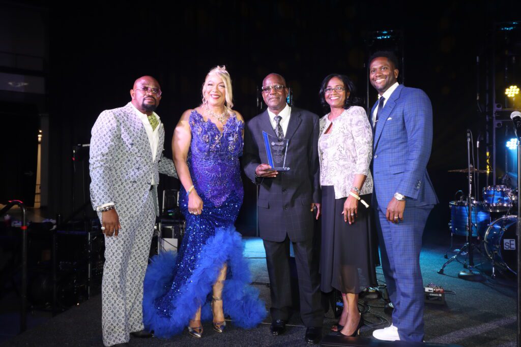 Group of five posing with award on stage