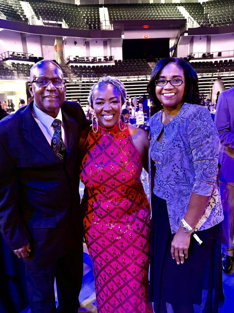 Three smiling adults posing at formal event