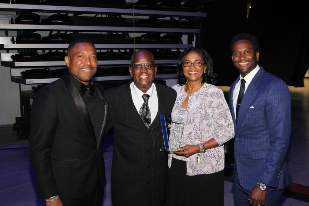 Four people in formal attire holding award
