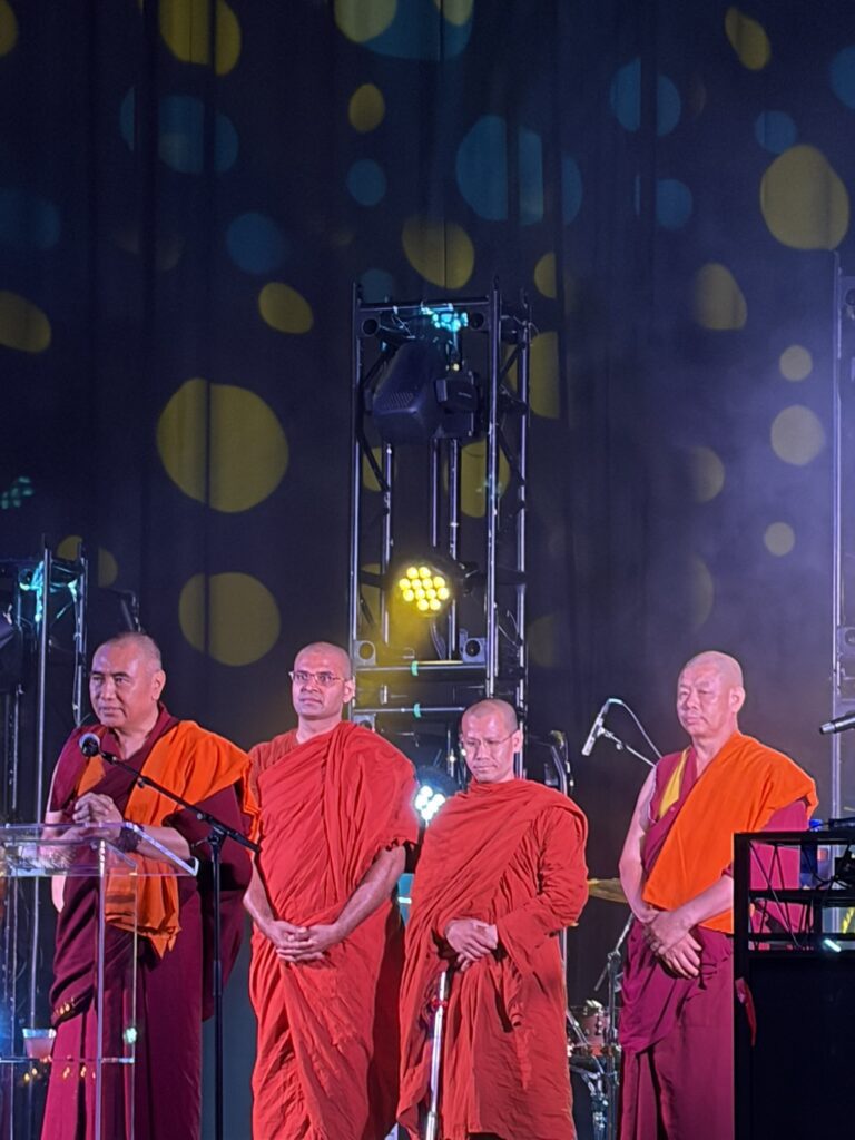 Four Buddhist monks in red robes on stage